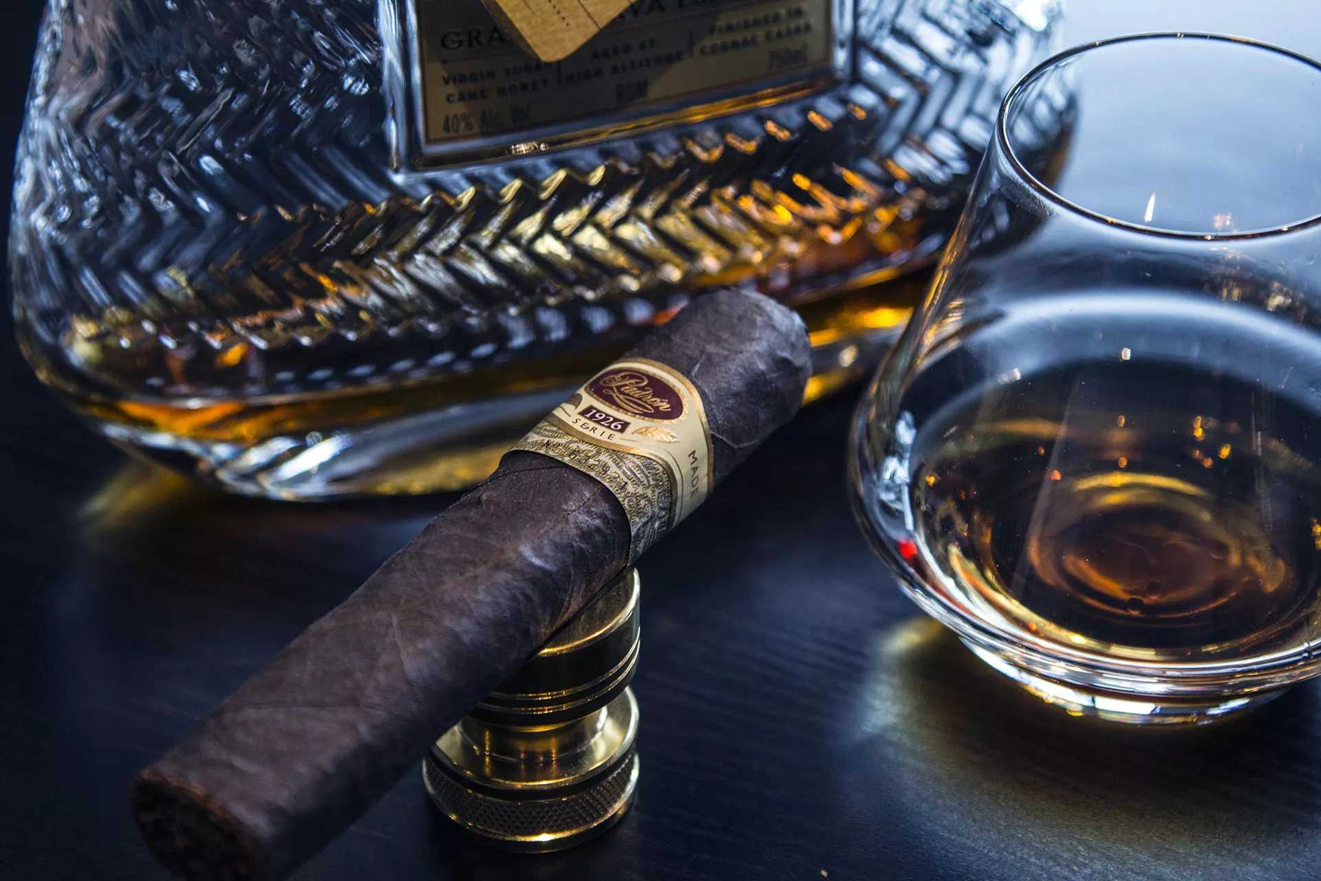 Cigar on stand next to a glass and bottle of liquor.